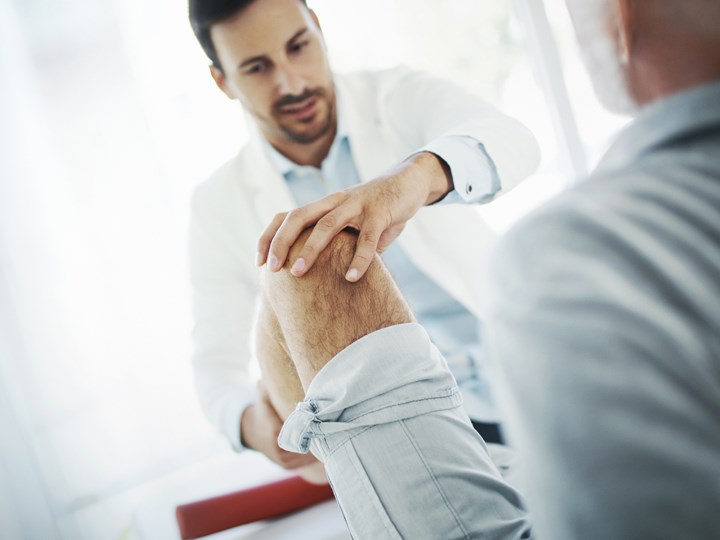 Arzt untersucht Beweglichkeit des Knies bei einem Patienten