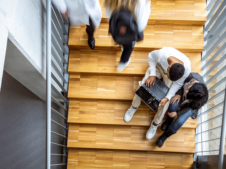 Studierende mit Laptop auf einer Treppe