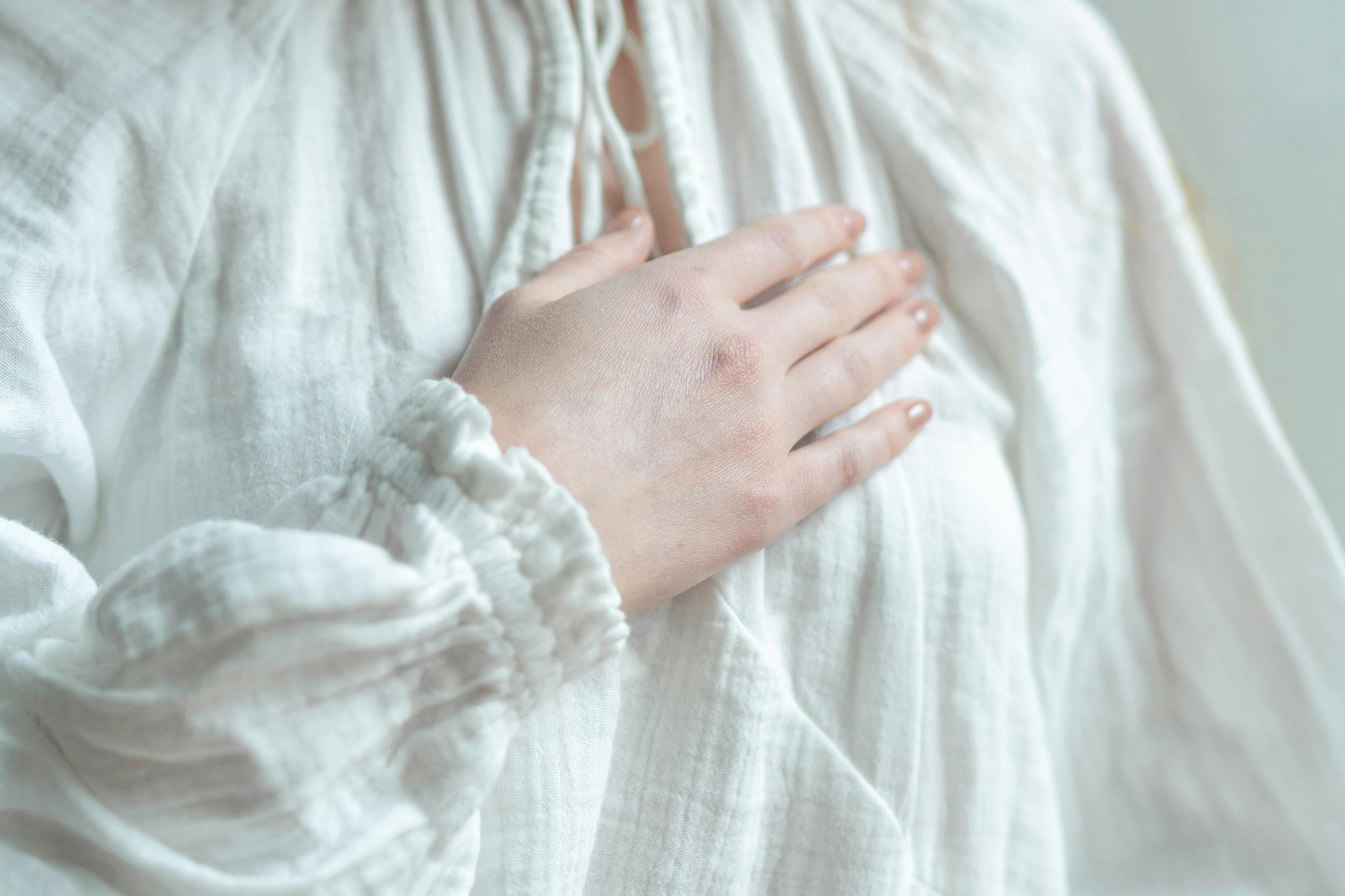 Frau legt ihre rechte Hand auf die linke Brust