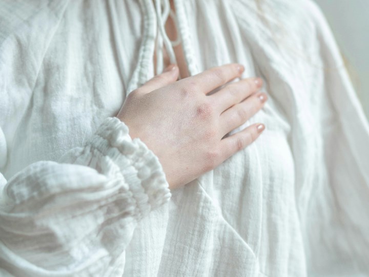 Frau legt ihre rechte Hand auf die linke Brust