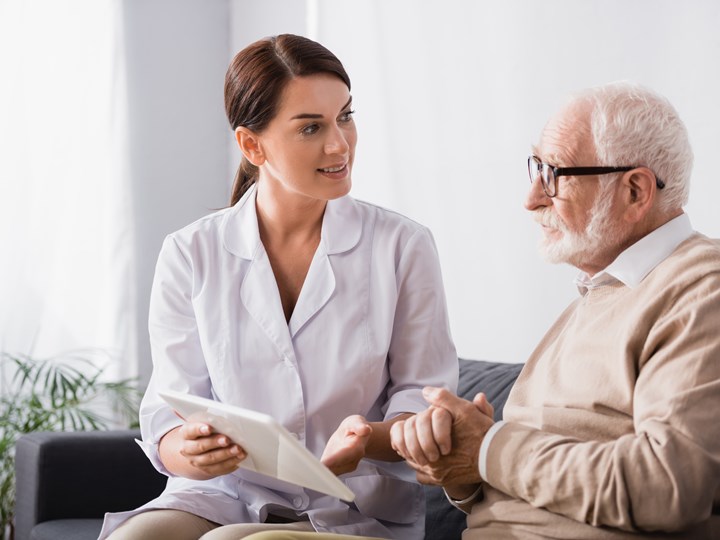 Psychologin mit Tablet spricht mit einem älteren Mann
