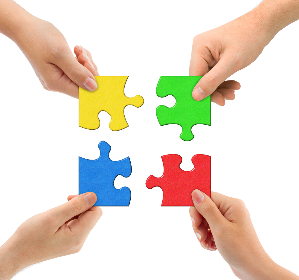 Vier Hände halten Puzzleteile