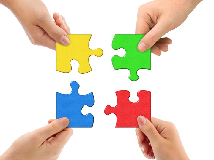 Vier Hände halten Puzzleteile