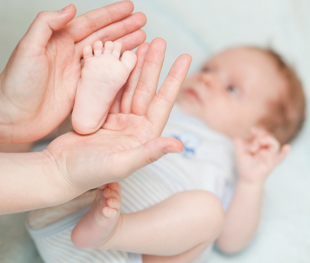 Füße eines Babys werden mit Händen gehalten
