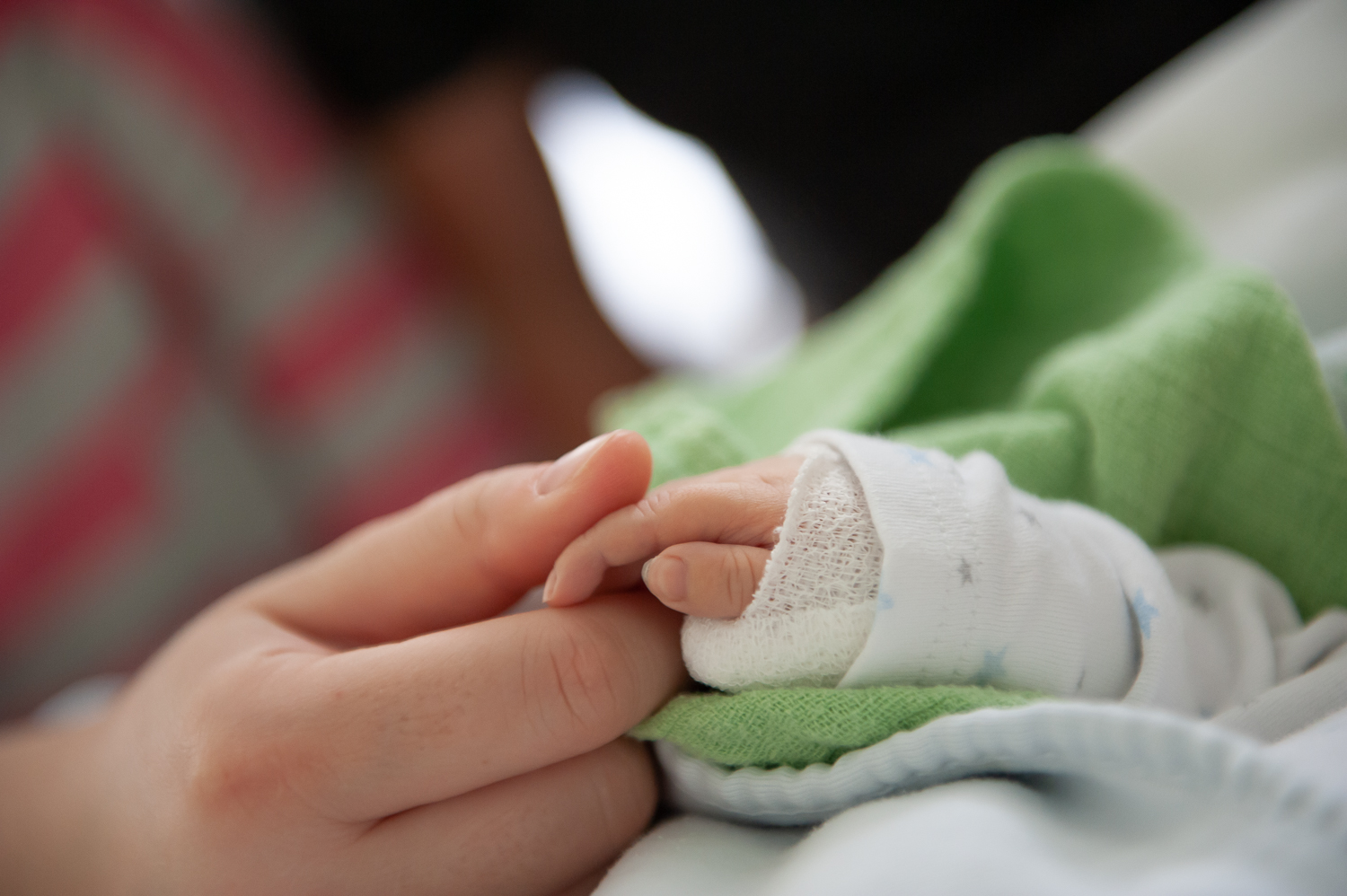 Hand eines Erwachsenen hält eine eingegipste Kinderhand